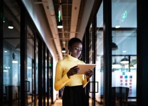 Young businesswoman walking and using digital tablet at corridor office