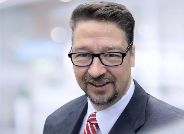 Headshot of a man wearing a suit and tie, with a blurred background. He is David Andrews of Aon.