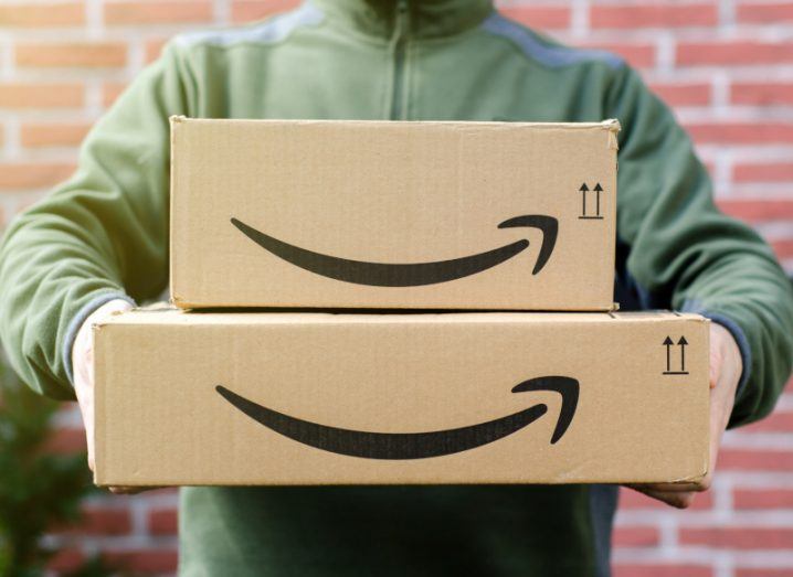 Amazon delivery person holding two packages with the Amazon arrow logo on them.