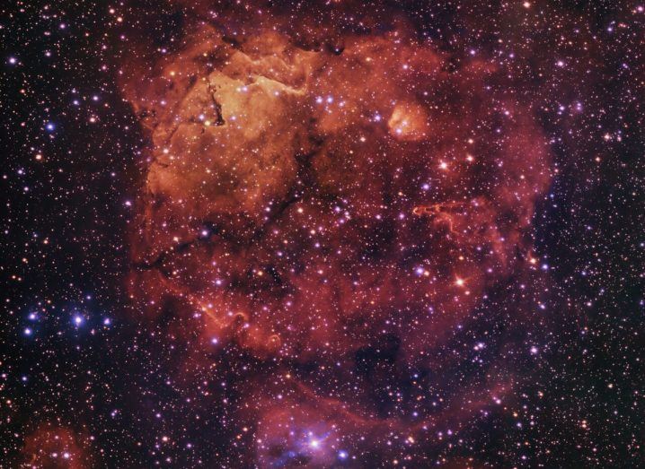 AN ESO image of the smiling cat nebula. It appears to be a big cloud of orange and red with the face of a cat smiling seemingly appearing out of it.