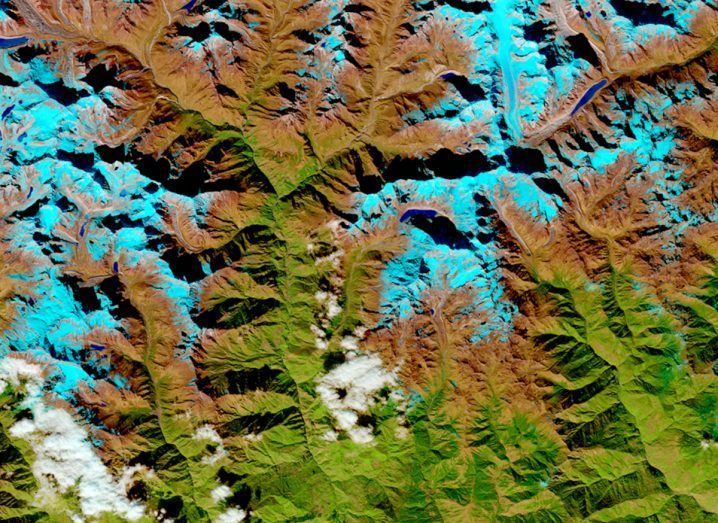 An image of the Earth as seen from space. Contoured land can be seen beyond patches of clouds.