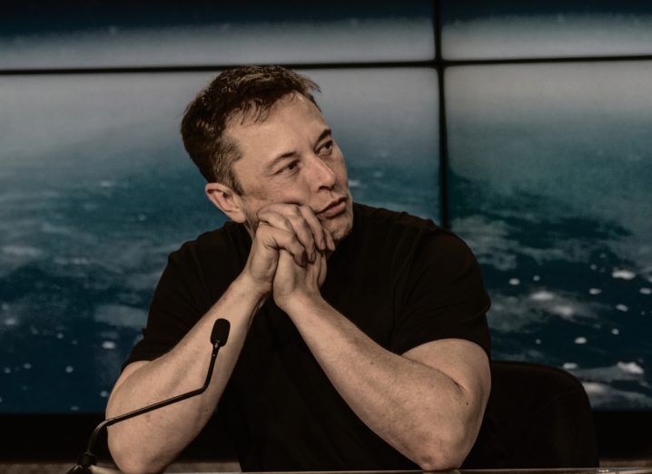 Image of Twitter CEO Elon Musk with his arms folded and his chin resting against his hands. He looks worried and the implication is he is concerned about Threads, the new social app by Meta.