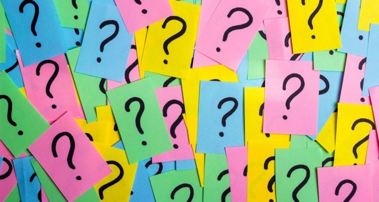 Lots of brightly coloured memo notes with black inked question marks on them.