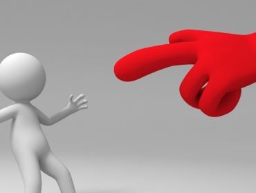 A red hand pointing at a figure which is leaning back as if stunned. Criticism concept.