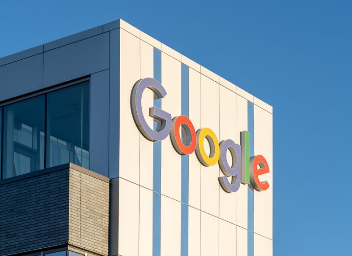 Google logo on the side of a building, with a clear blue sky in the background.