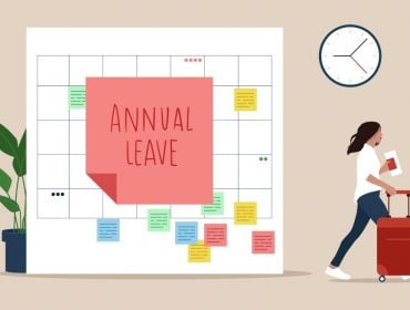 An illustration of a giant calendar with a sticky note labelled 'Annual Leave' stuck in the centre. There is a woman to the right of the calendar walking with a suitcase.