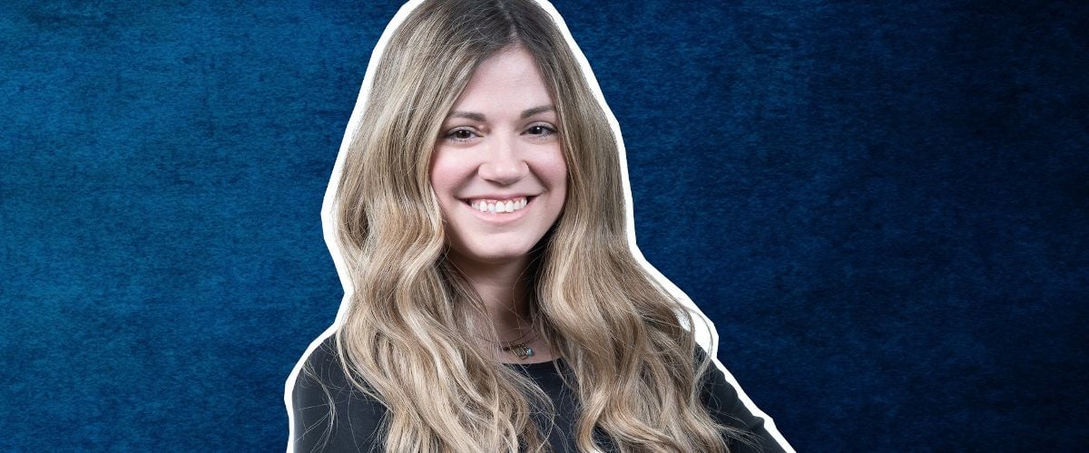 A headshot of a woman with long hair smiling at the camera against a blue background. She is Christina Gialleli.