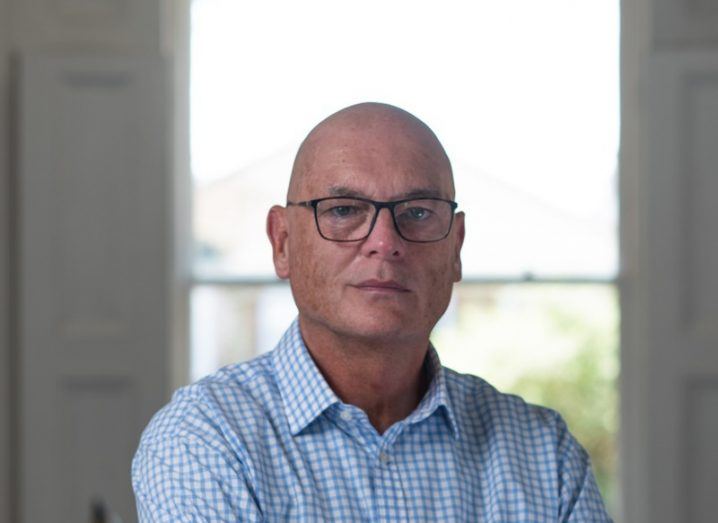 Headshot of a man in a blue shirt in front of a window. He is Mike Allen of Verne Global.
