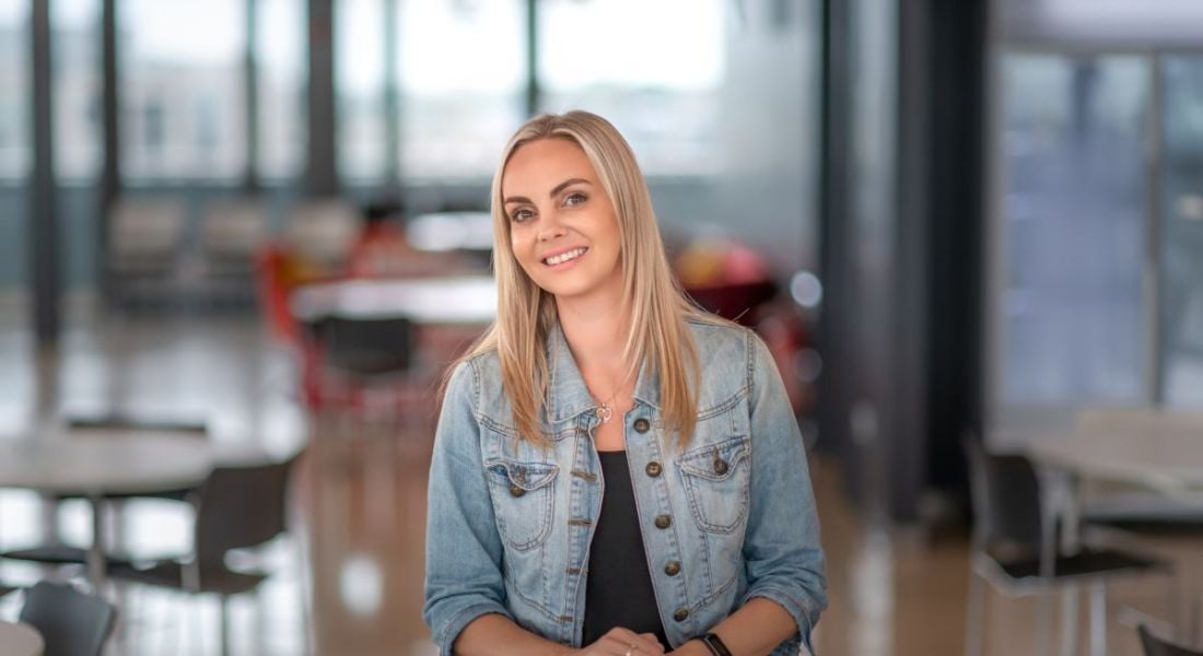 A young woman wearing a denim jacket sitting in a bright common area in an office. She is Philippa Maleney of Yahoo.