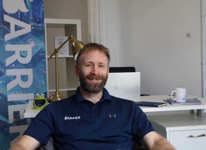 A man sits in an office with a banner displaying the Barrier Networks company name. He is Ryan McConechy, Barrier Network's CTO.