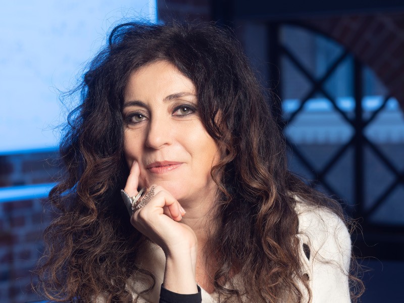 A woman with long brown curly hair smiles at the camera. She is Prof Sabrina Maniscalco, a quantum computing expert.