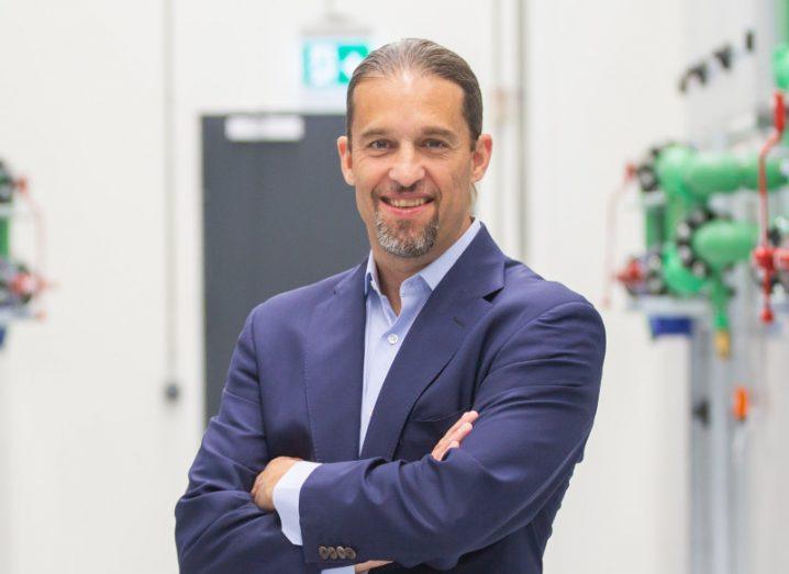 A man wearing a navy suit smiles at the camera with his arms folded. He is Tate Cantrell, CTO at Verne Global.